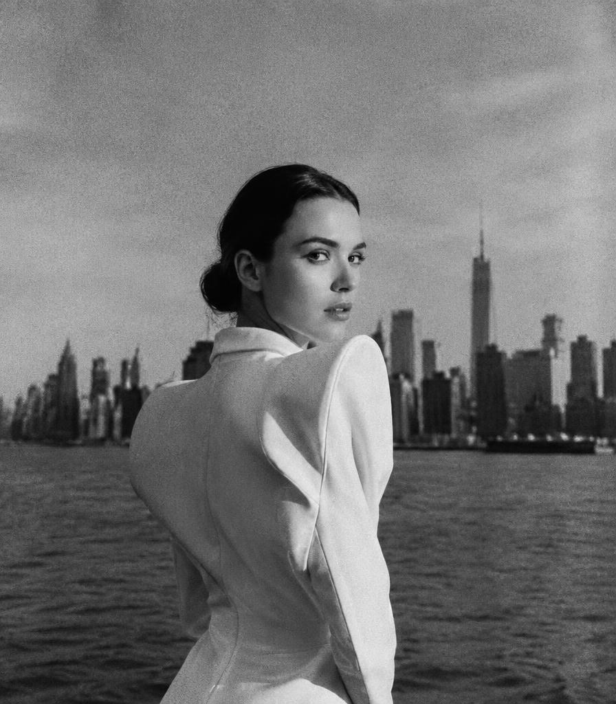 Black and white portrait in a structured white jacket against a skyline